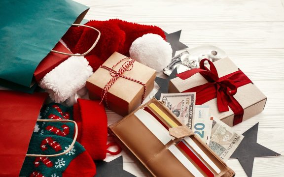 Christmas  shopping and sales concept. Credit cards and money in wallet, paper bags with clothes, stockings, gift boxes, jewelry on white rustic background. Seasonal advertising and sale